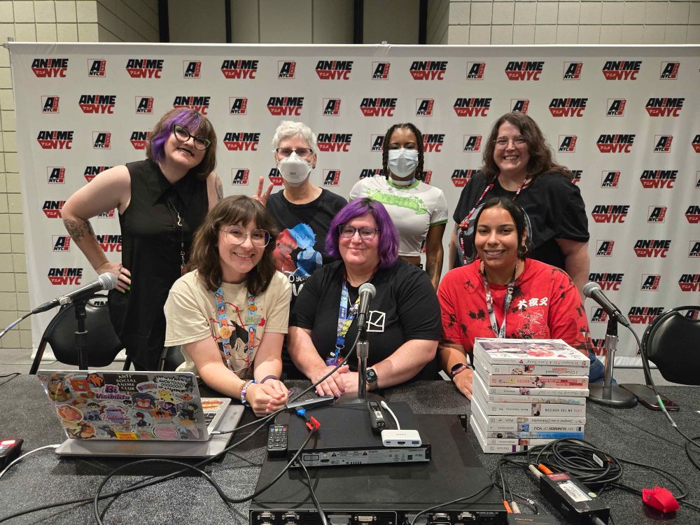 Photo of the panelist of Finding Your Story: Manga Recommendations for Queer Reads.
Back row, standing, L to R: Morgan Perry, Erica Friedman, Princess Weekes, Whitney Leopard
Front row, sitting, L to R: Sara Munson, TJ Ferentini, Lisa De La Cruz