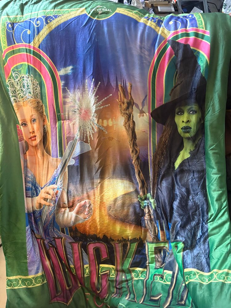 Full shot of Wicked blanket featuring Ariana Grande as Glinda on the left holding a wand and Cynthia Erivo as Elphaba holding her broomstick.