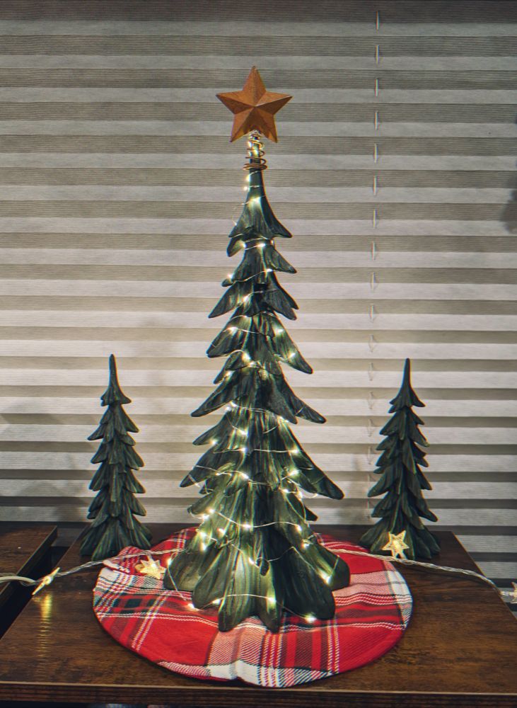 A cute lit wooden tree with two smaller matching trees at its sides.