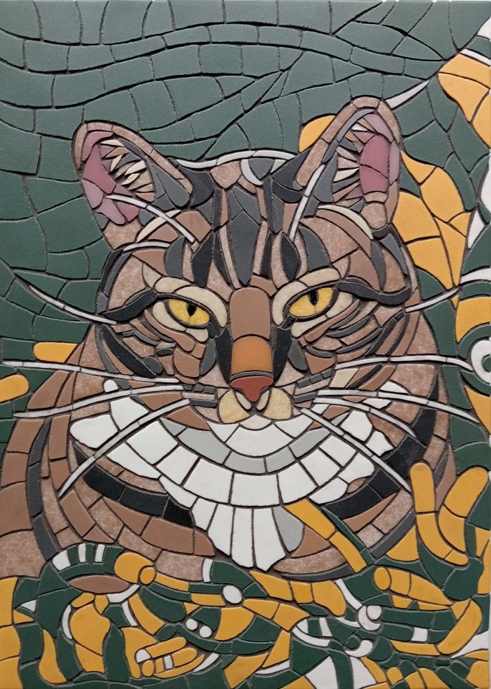 The grouted version of a mosaic of a tabby cat with yellow eyes lying on a "green bay packers" blanket.