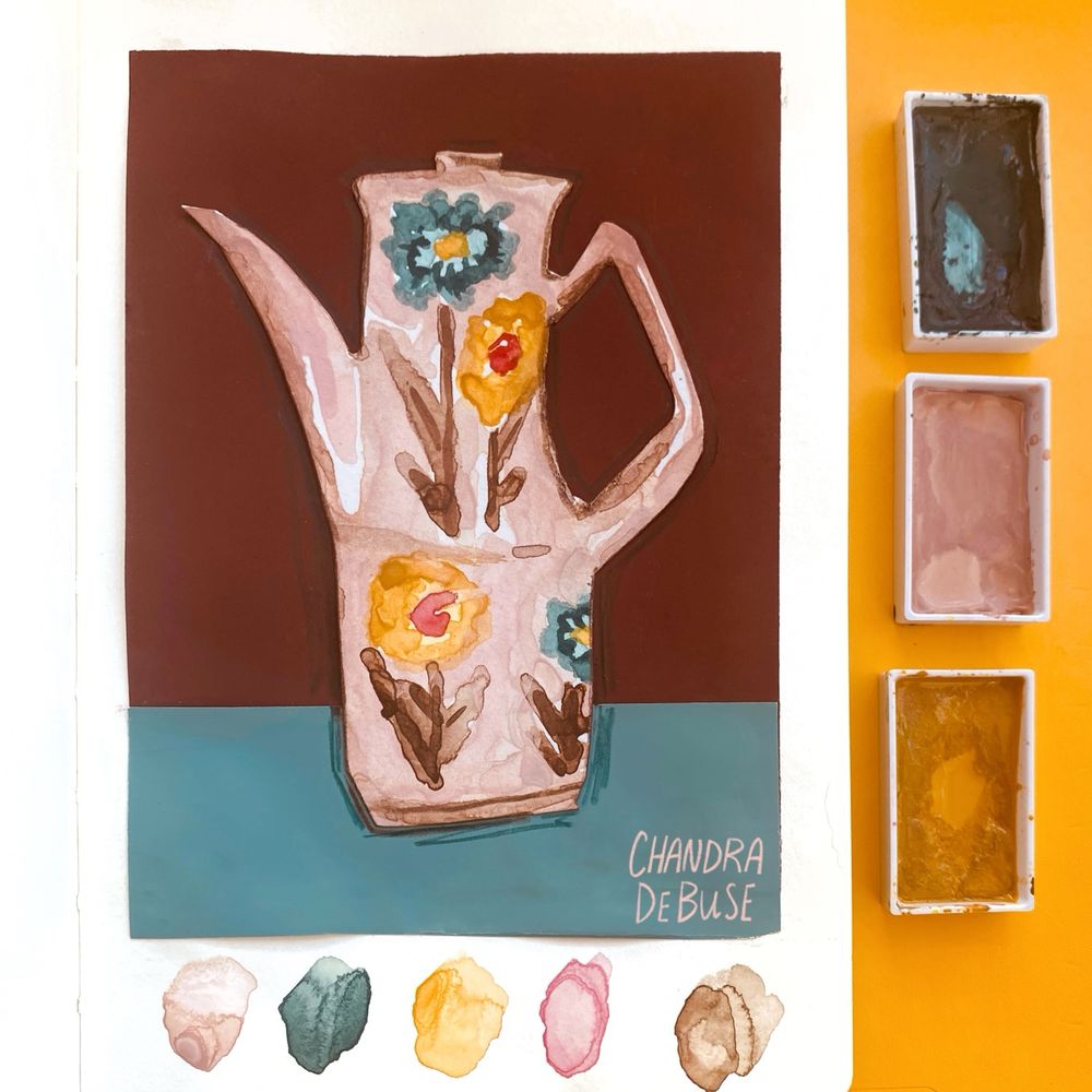A pink teapot painted with watercolors. There are four flowers on the teapot in Bluegreens and Warm yellows. The stems are brown. Outside of the picture frame are three paint pans and five watercolor blobs in the colors of the artwork.