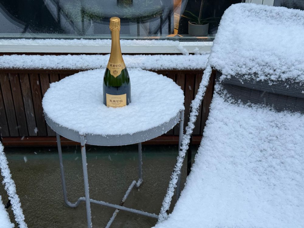 A bottle of Krug Champagne sitting on top of a snow covered table