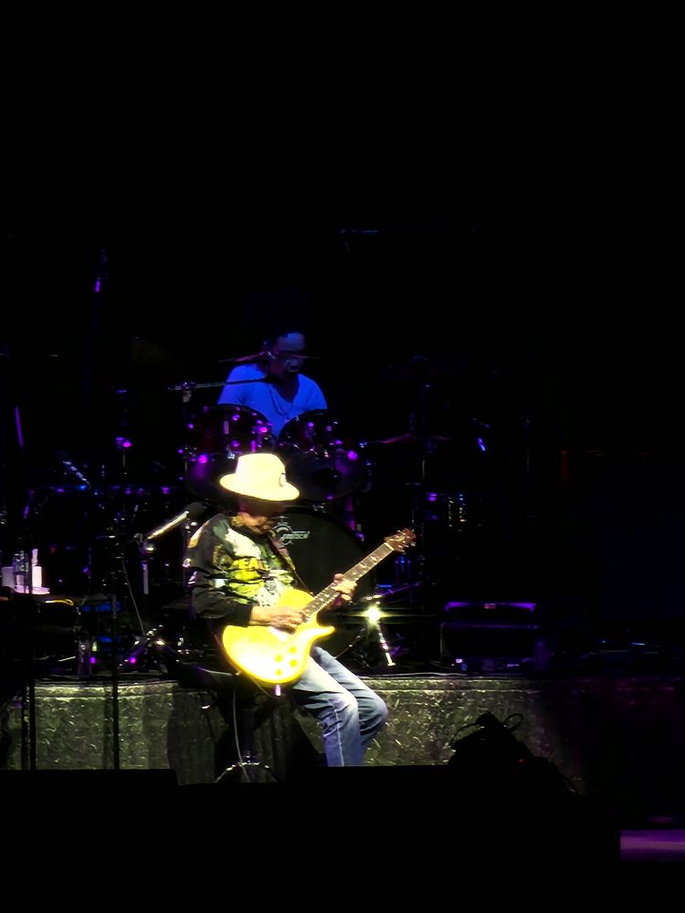 Carlos Santana jouant de la guitare (au fond la batteuse)