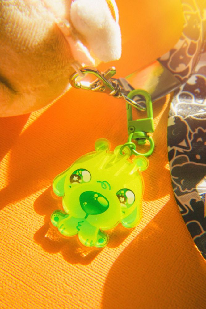 a photograph of an alien dog keychain. it glows bright green in the sunlight