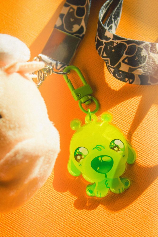 a photograph of an alien dog keychain. it glows bright green in the sunlight
