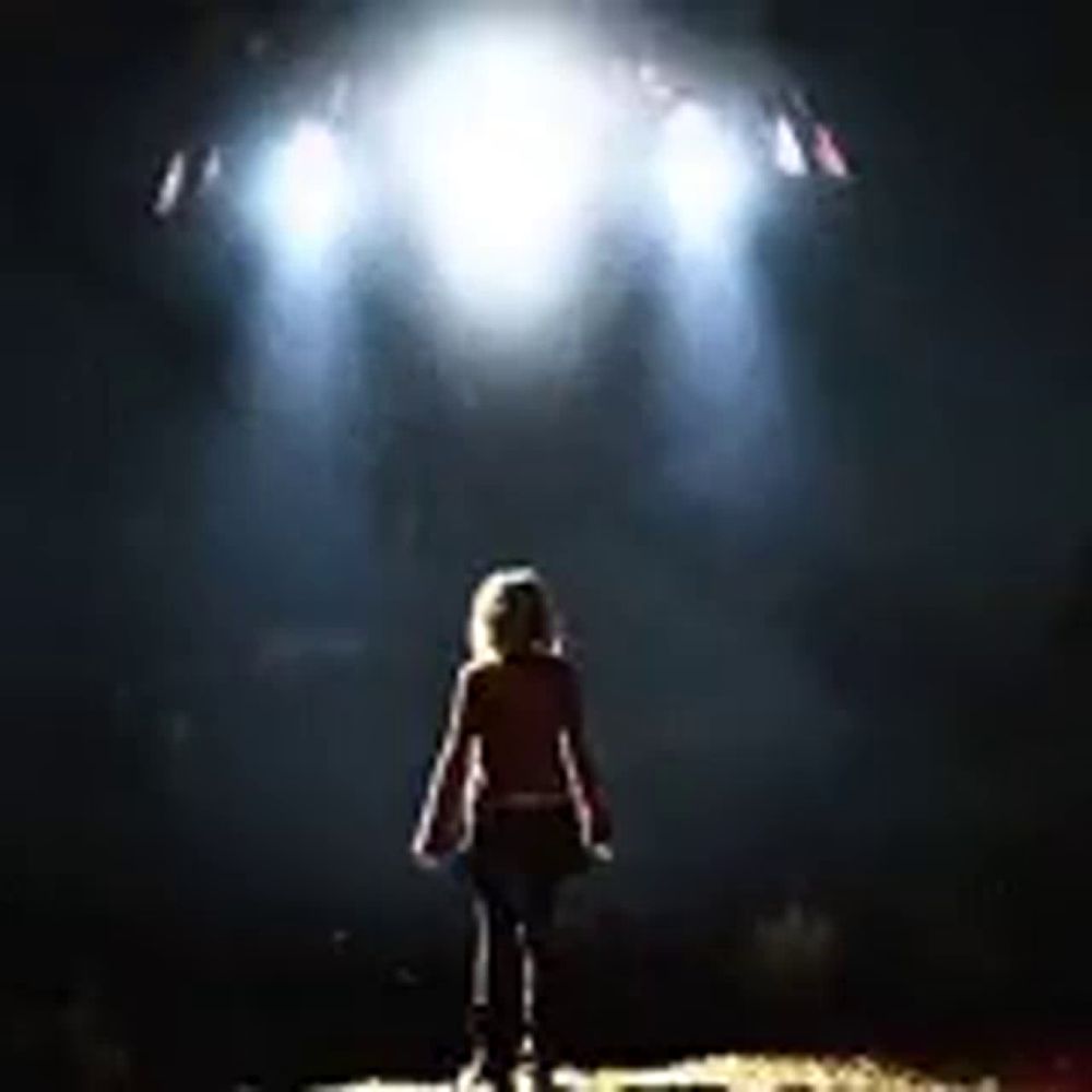 a woman is standing in front of a stage with a lot of lights shining on her .