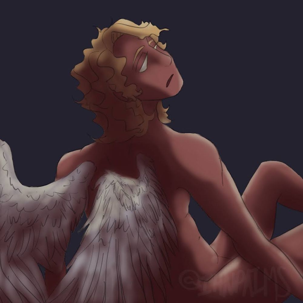 Man with long blonde hair and angel wings sitting with hos back turned to the audience 