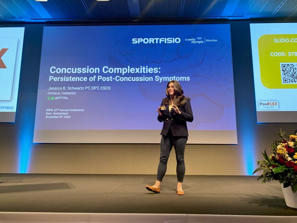 Jessica Schwartz, Physical Therapist and Brain Injury Survivor, delivering a lecture in a blue suit to 500+ Fisio’s on Concussion Complexities