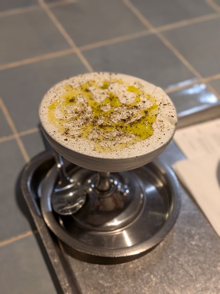 金属製のカクテルグラスに入ったジェラート。本体は塩味で上にはオリーブオイルと黒コショウがかかっている。