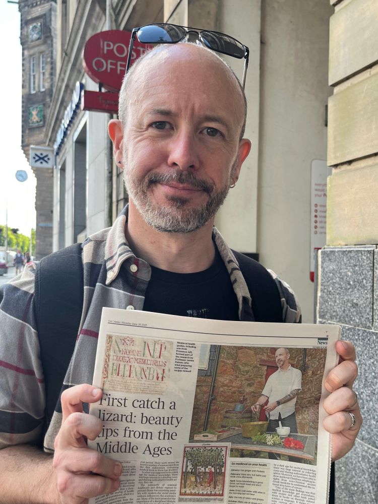Beardy professor holding newspaper 