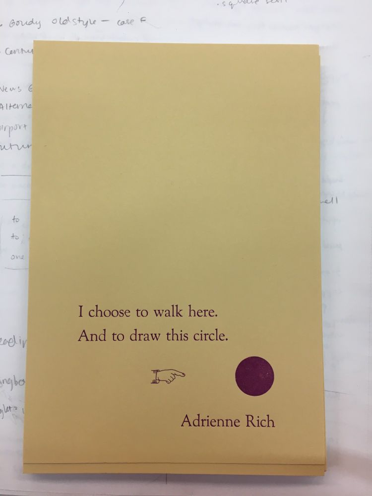 "I choose to walk here. And to draw this circle. Adrienne Rich." The text is a letterpress print in violet ink on yellow paper, with a letterpress ornament of a hand pointing to a full purple circle. The print is part of a stack which lies on white paper with a handful of pencil scribbles.