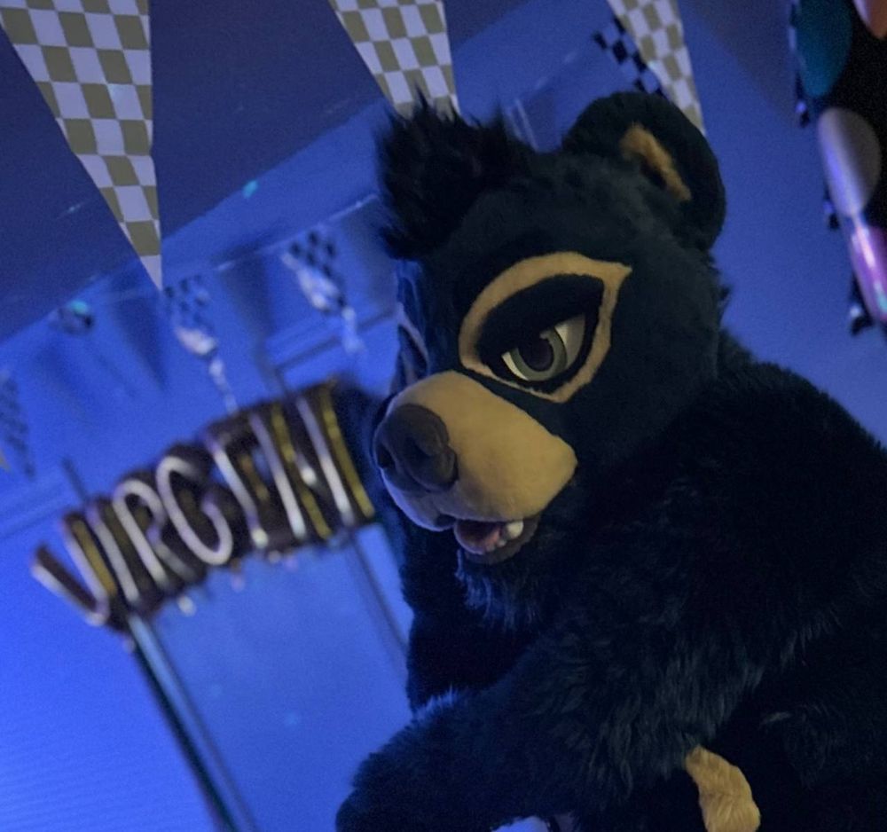 monty sitting in a seductive pose with a spread of balloons behind him that spell out "virgin"