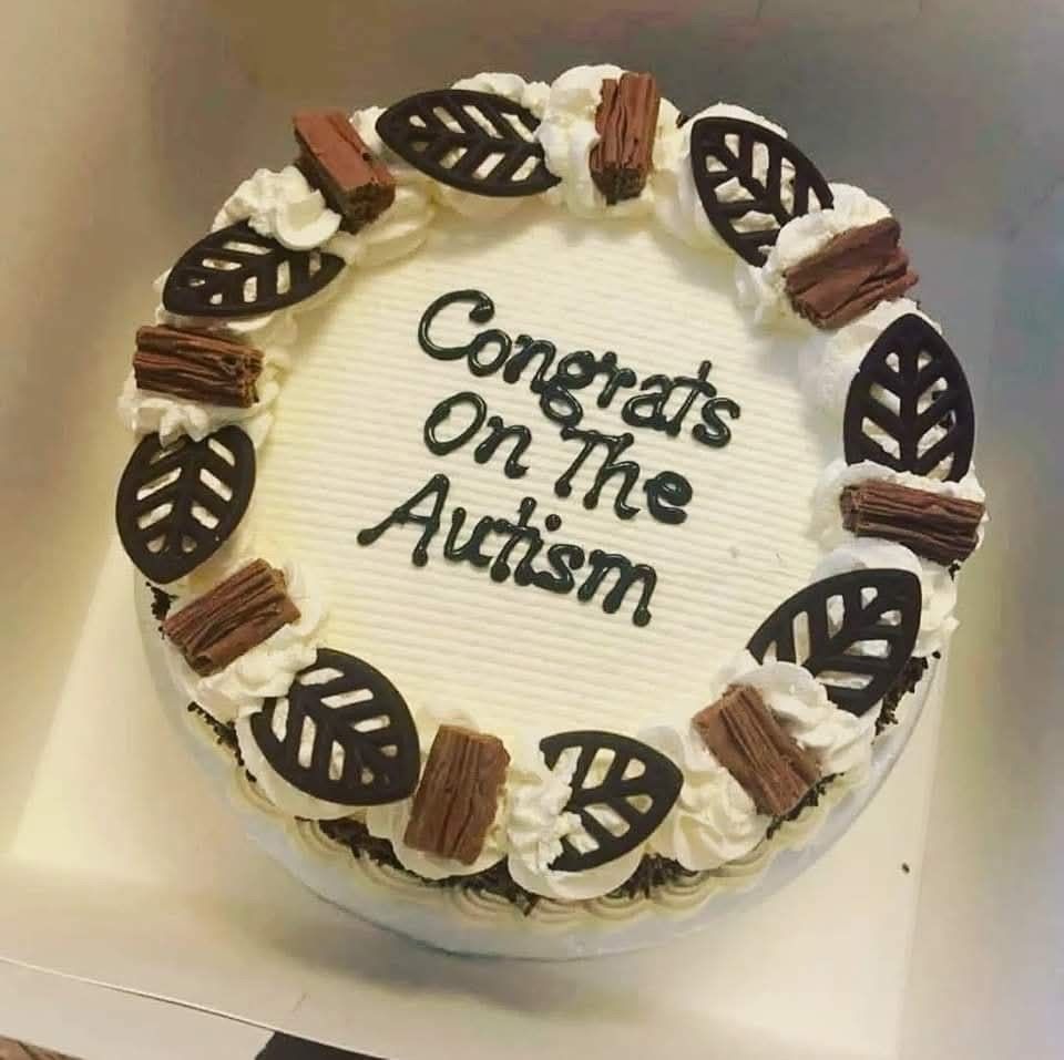 A picture of a white iced cake with chocolate decorations. The message iced on the cake says, “Congrats On The Autism”.