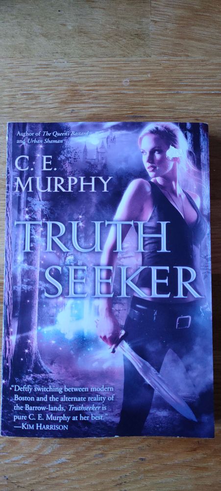 A photograph of the front cover of the novel Truth Seeker by C. E. Murphy.

It shows a blonde woman wearing dark jeans and a dark tank-top holding a leaf-bladed sword in one hand and looking back over her shoulder with a determined expression on her face.