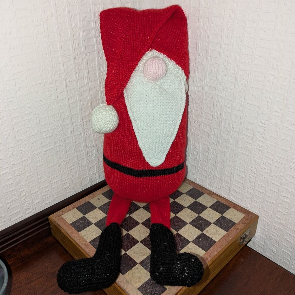All three shots show a gonk style santa. He has a droopy hat and long flat legs.
In this picture he is sat down with his legs straight in front. 