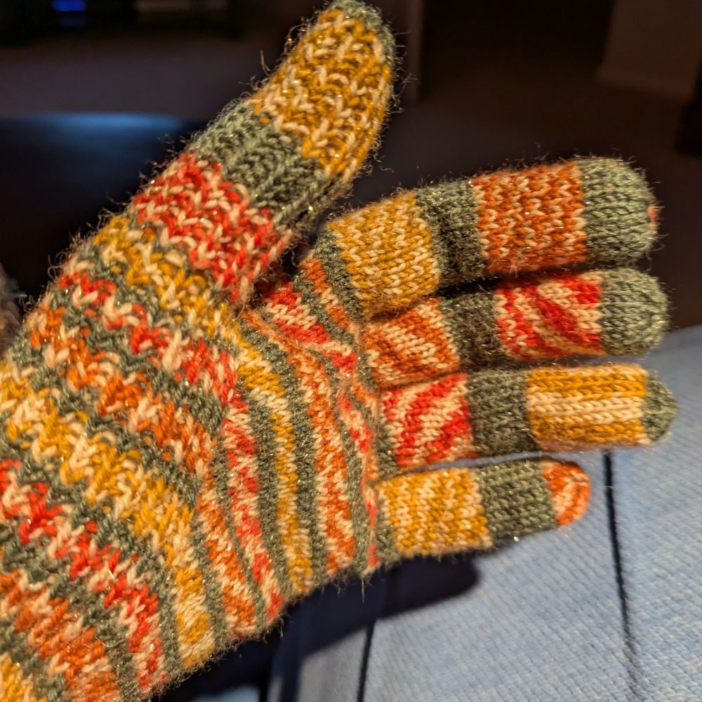 The left hand glove. Hand knitted in Christmas self striping yarn.