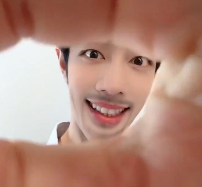 A screenshot from Xiao Zhan’s latest douyin video using a filter that gives him a fake goatee and enlarges features of his face. He’s peeking through his fingers that he’s holding up close to the camera lens
