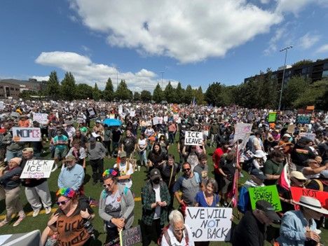 Crowd of people at Cal Anderson Park with signs. Council President Sara Nelson stands among the crowd with a sign that reads "We will not go back". 