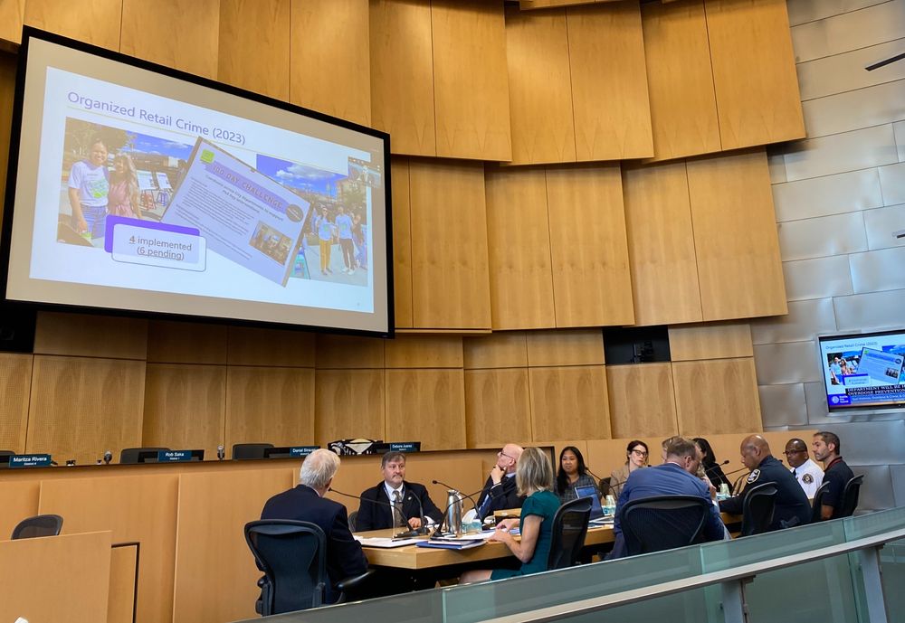 Seattle public safety leaders seated at a conference table in front of a projector screen displaying City Auditor reports. 