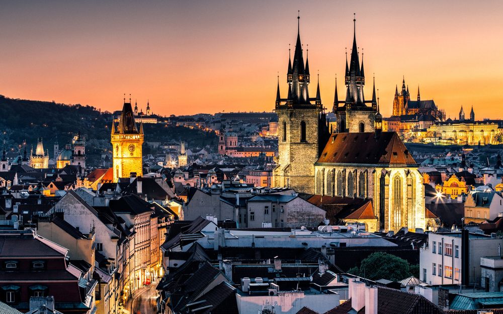 A view through many Prague towers towards a sunset.