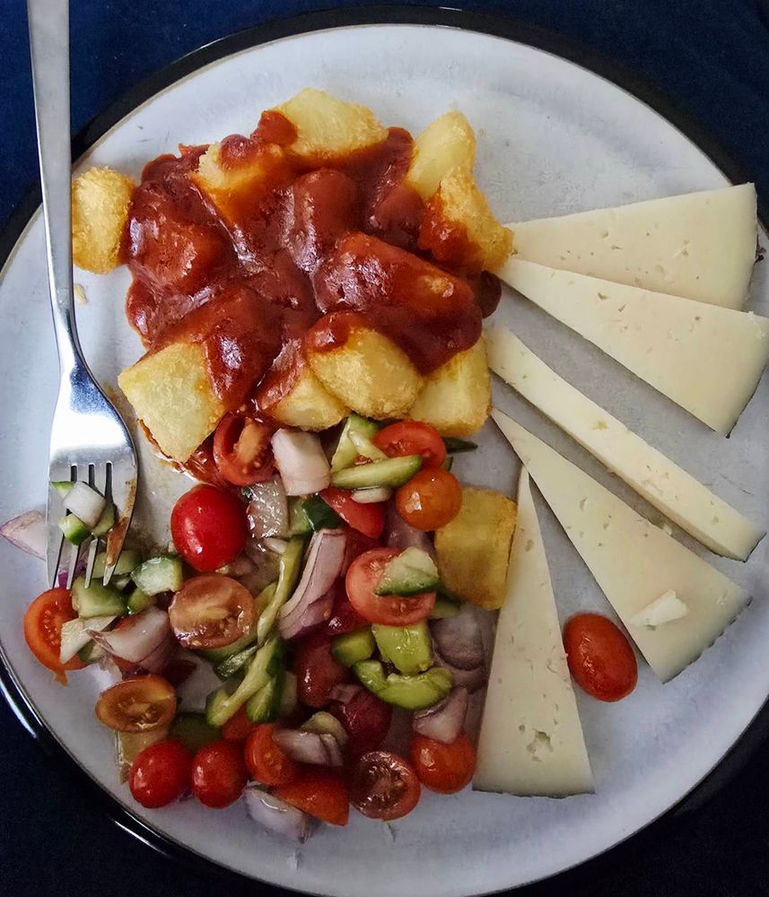 Patatas bravas, manchego, and a salad of tomatoes, cucumber, and onions 