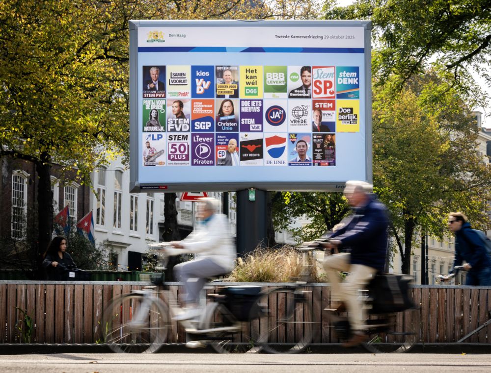 Fietsende mensen langs verkiezingsbord. ANP