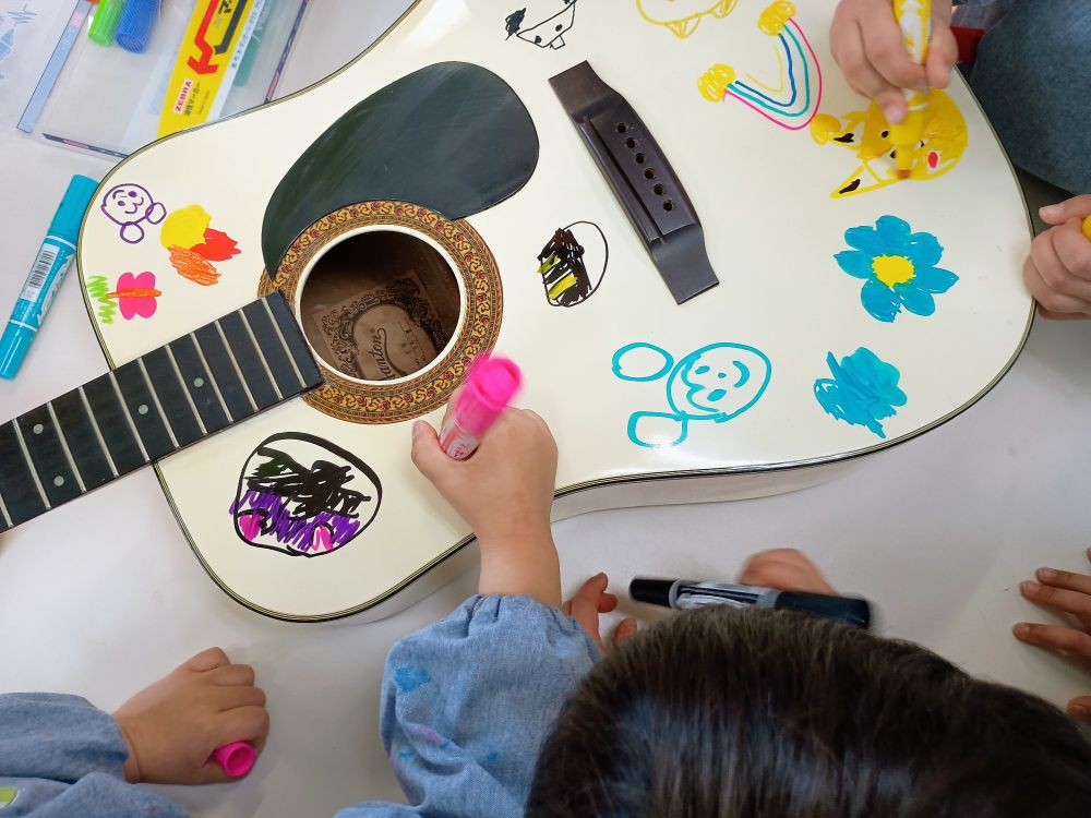 Children decorating an cheap old guitar