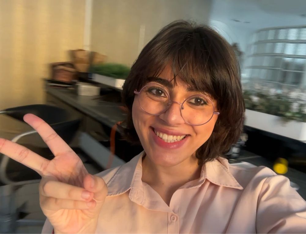 Roma com maquiagem lápis de olho com leve blush no cabeleiro girando a cadeira com camisa social rosa e pulseira combinandinho com a namorada de borboleta na cor bordô