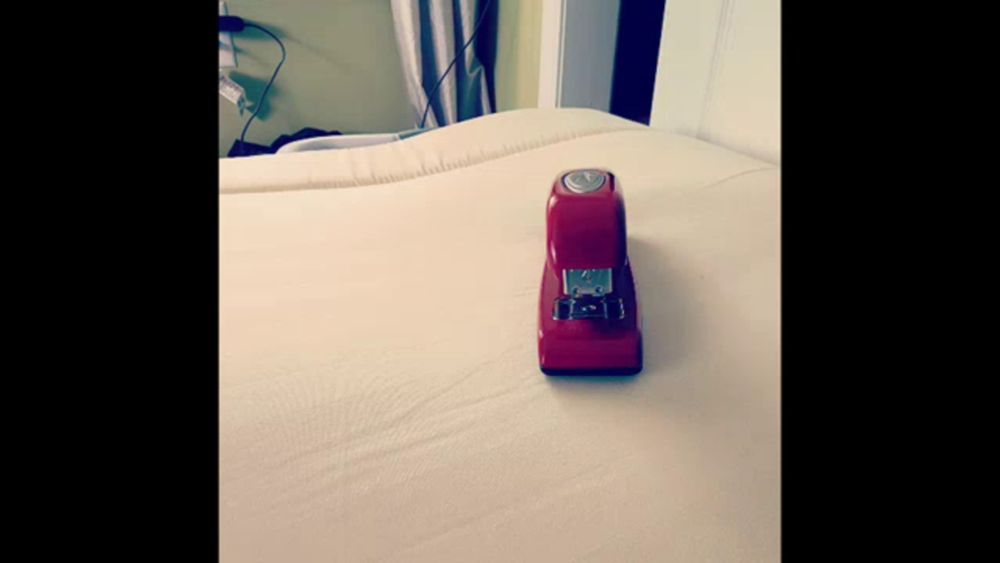 a red stapler is sitting on top of a white blanket