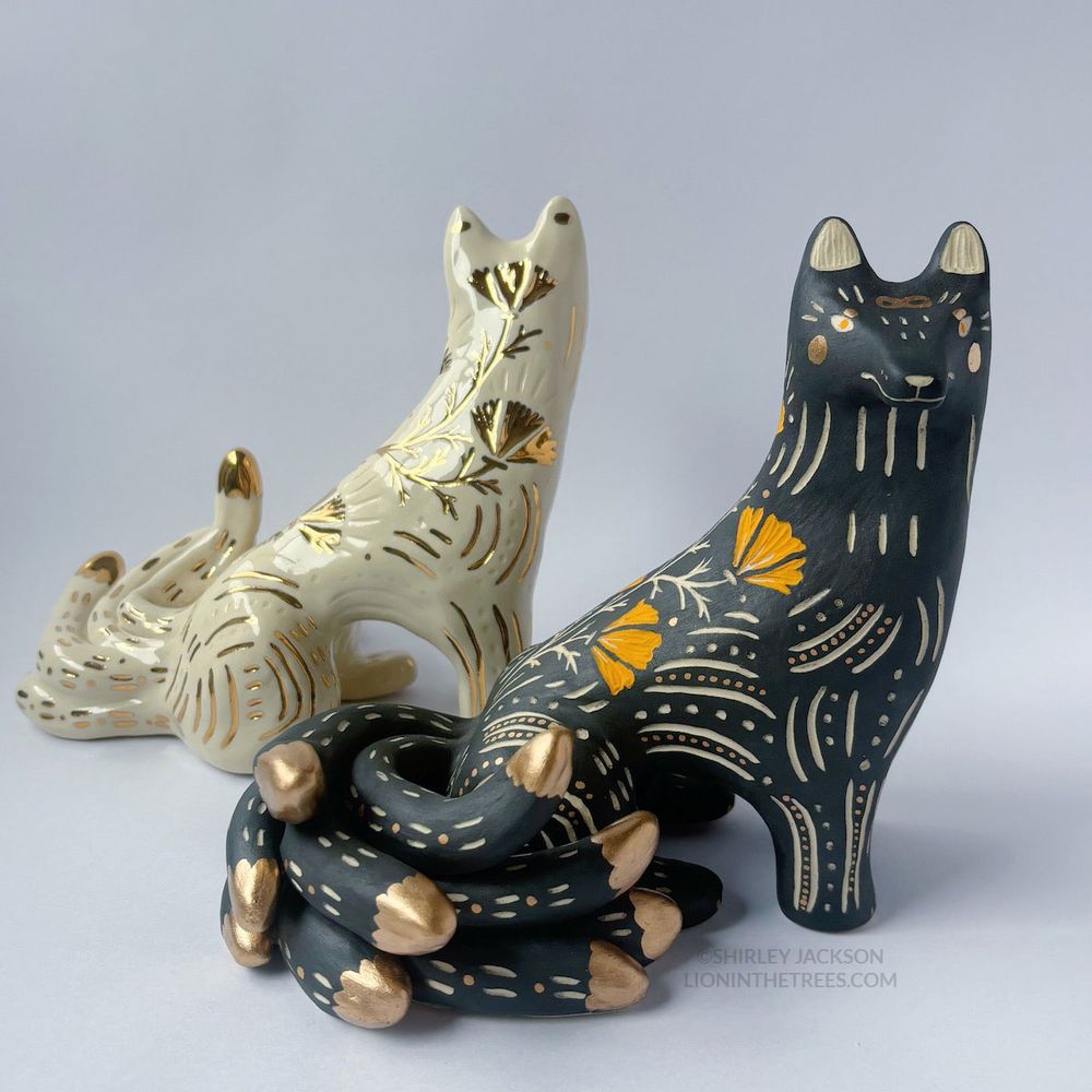 Two large sgraffito kumiho sculptures. The black/gold version is positioned in the foreground facing the viewer with the white/gold version showing it's back in the background.