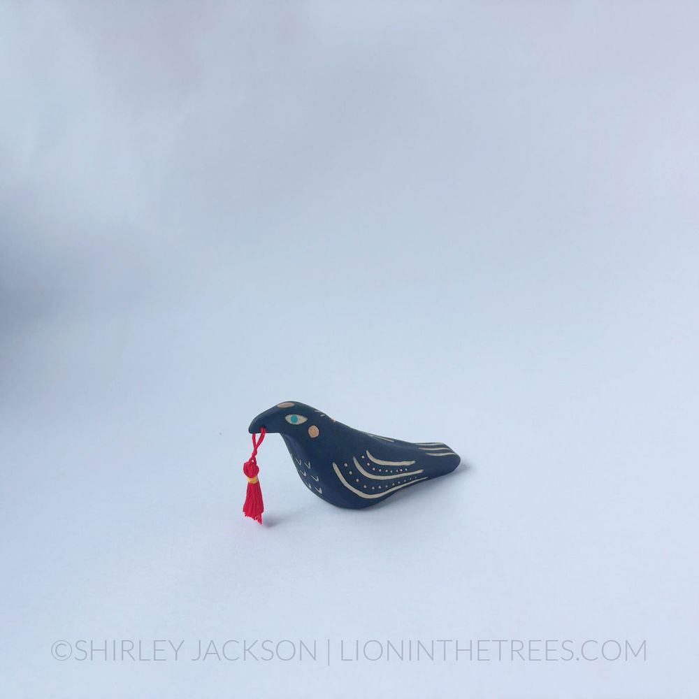 Black raven totem done with various underglaze, gold gilding, and a handmade red tassel.