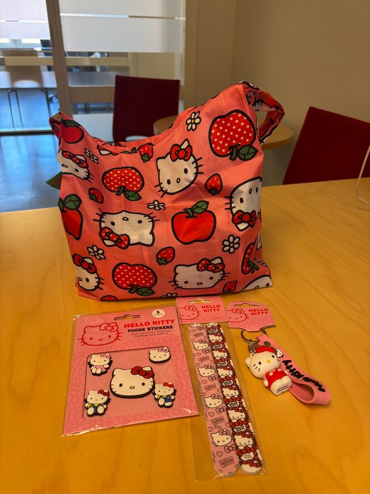 Hello Kitty handlenett, klistremerker, neglefiler og nøkkelring på kontorpult med kommunal estetikk rundt