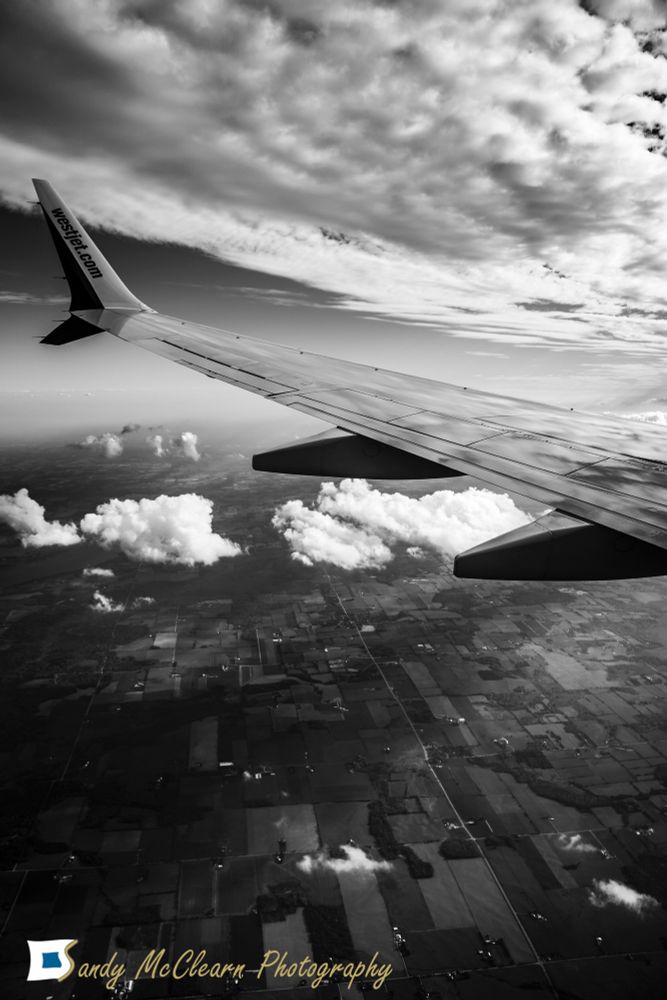 View from airplane window of the wing over farmland. 