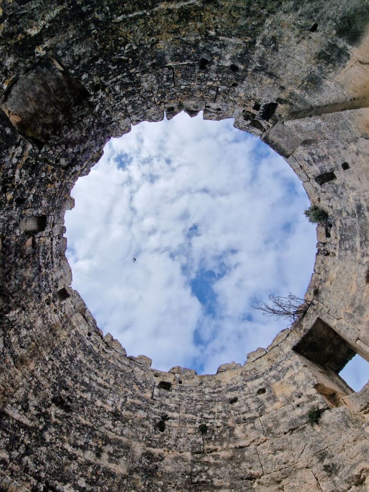 Une tour sans toit qui laisse voir le ciel et les nuages .