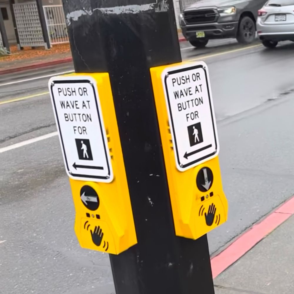 Two Campbell Guardian Wave audible push-buttons. One with a tactile arrow pointing to the left. The other button has the arrow pointing down to the ground.
(Quadra St at Caledonia Ave)