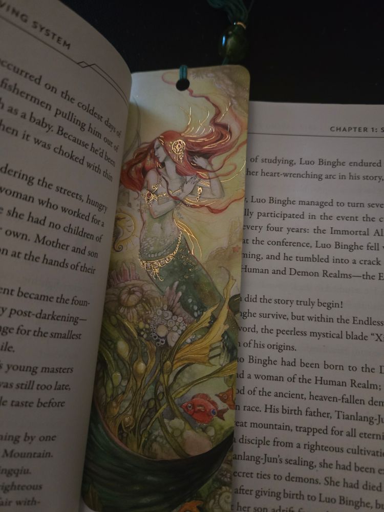 Bookmark showing the image of a mermaid inside of a novel.