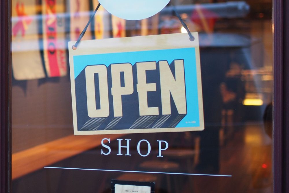 A sign hanging from a shop window that reads "Open."