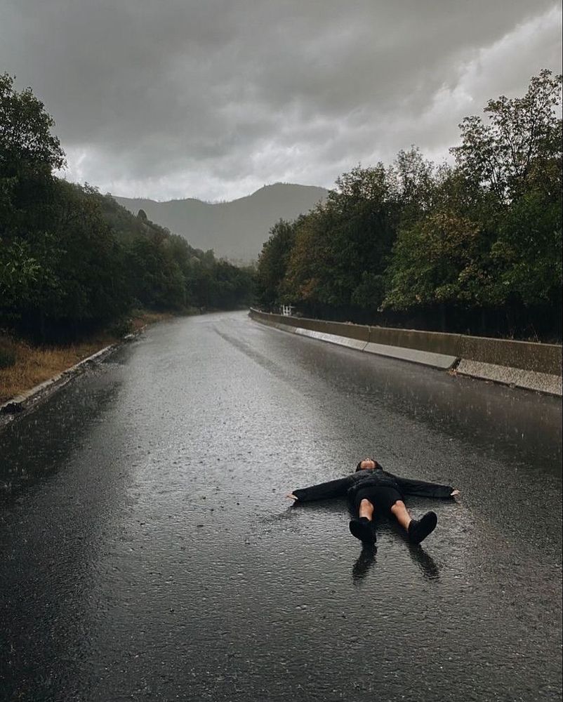 someone laying down on the road on a rainy day