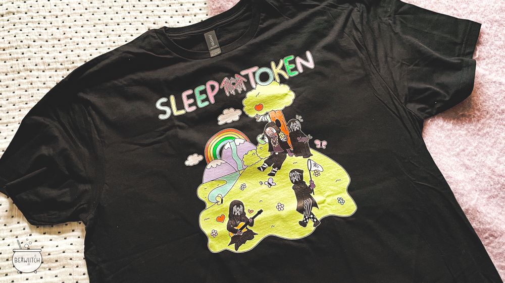 black sleep token shirt with vessel and ii sitting under a tree, iii catching butterflies with a net and iv playing the guitar. the band name is at the top in pastel colors