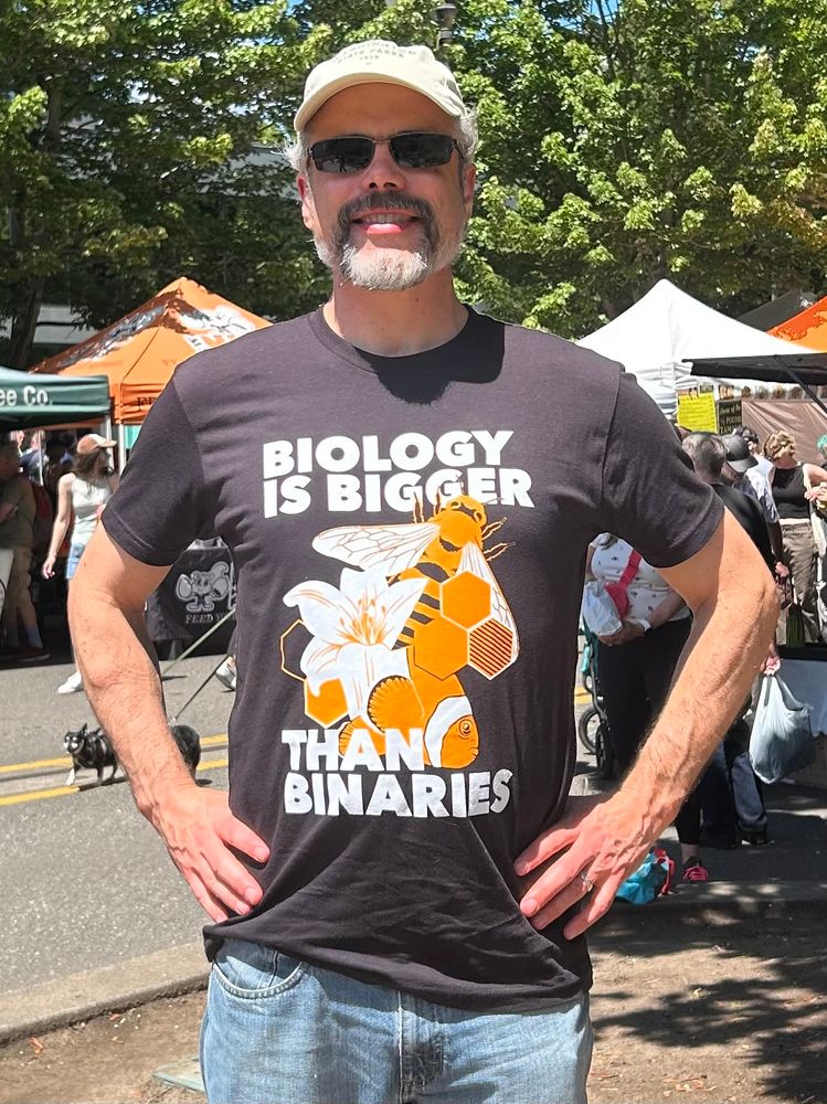 A biologist wearing a black t-shirt that says: Biology is bigger than binaries