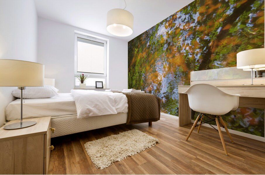 A large, impressionistic mural of a pond with green and orange Autumn leaves and blue water  on a bedroom wall.