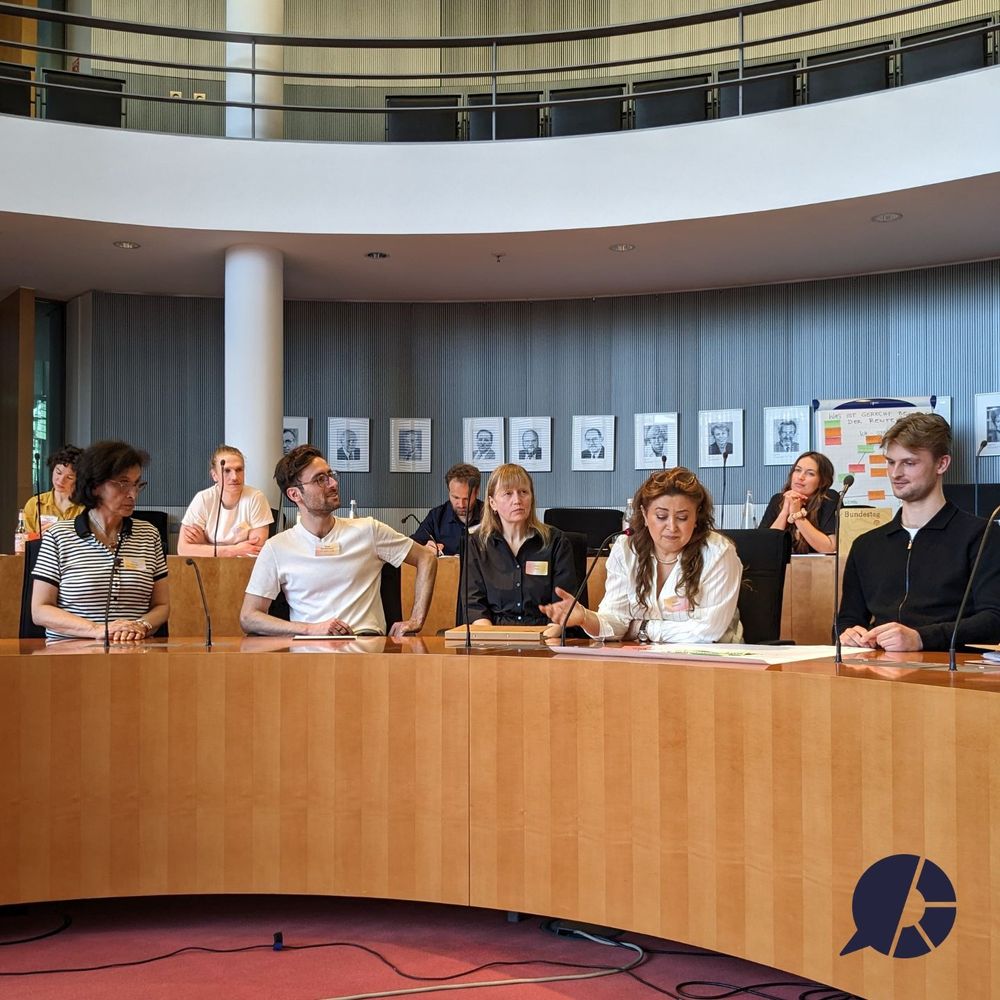 Canan Bayram (MdB, Bündnis 90/ Die Grünen) tauscht sich mit einigen Teilnehmenden aus, in einem Sitzungssaal des Bundestages.