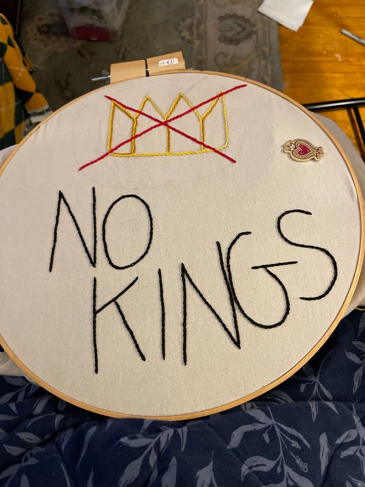 Embroidered No Kings protest sign with an x'ed out crown. 