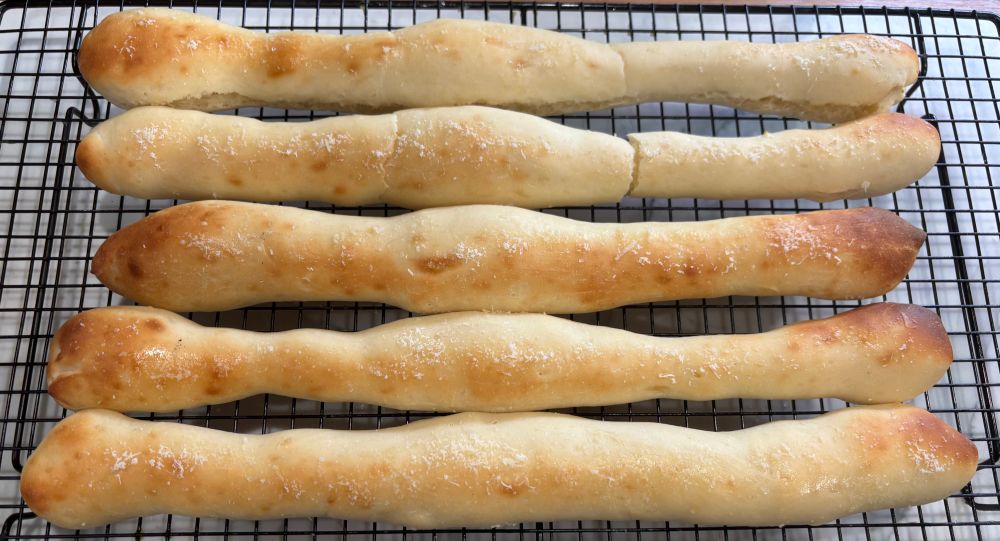 Five breadsticks on a cooling rack.