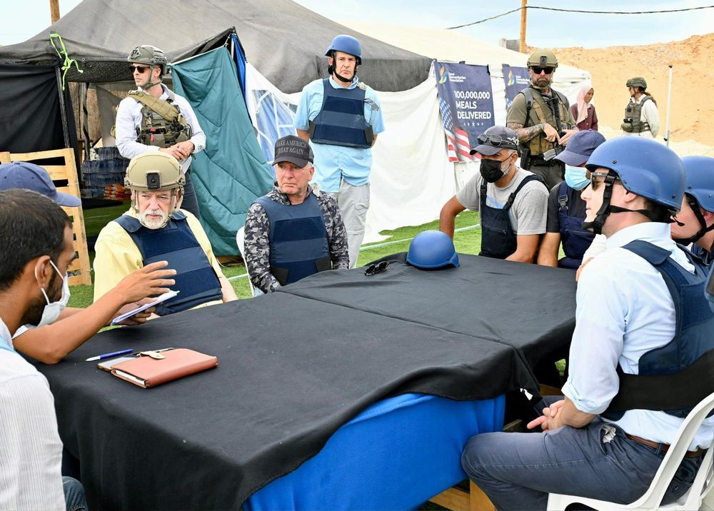 US special envoy Steve Witkoff and American ambassador to Israel Mike Huckabee sit at a table listening to a speaker while at a Gaza Humanitarian Foundation site in Gaza 