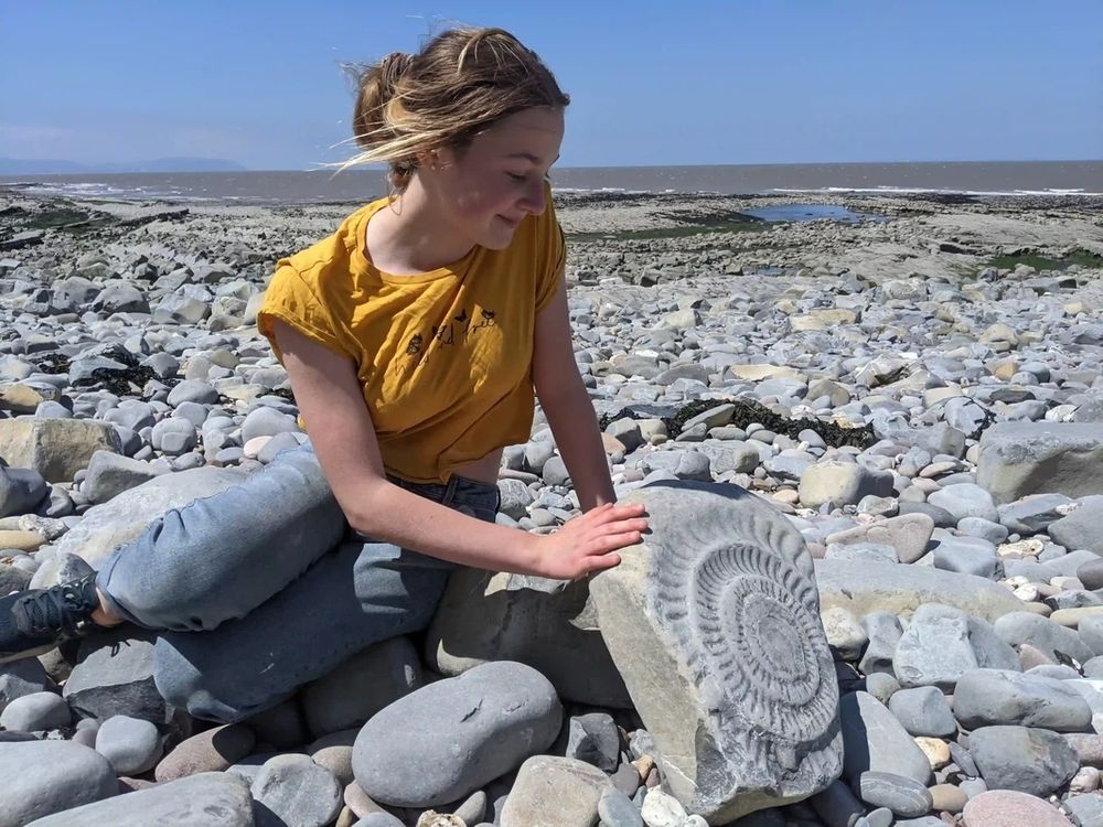 A woman with an ammonite on a beach 
