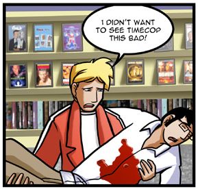 Rob, a blonde guy wearing a red jacket, holds his bleeding roommate Elliot, a black-haired guy with square glasses. Rob is cradling Elliot in his arms in front of a display of DVD boxes on shelves. "I didn't want to see Timecop this bad!" Rob says forlornly.
