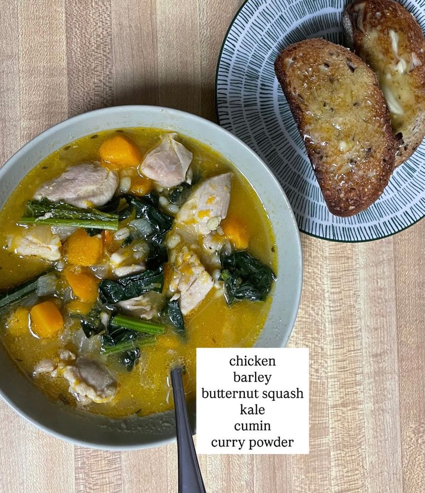 A bowl of soup with chicken, barley, butternut squash, kale, cumin, and curry powder, and a plate with two slices of buttered whole grain toast