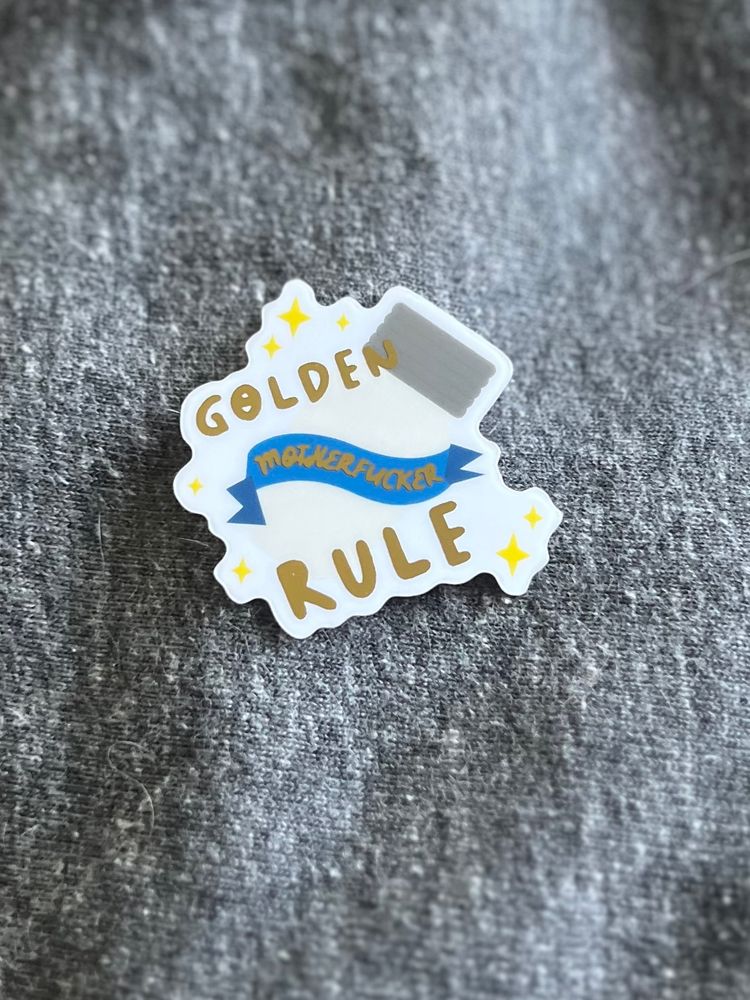 A sticker featuring a vial. The words “Golden Rule, Motherfucker” are in a gold, metallic foil.