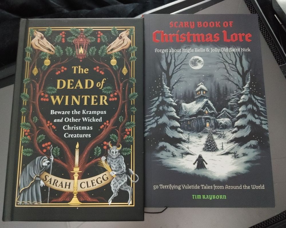 Two winter holiday-themed books placed side by side. The book on the left is titled "The Dead of Winter: Beware the Krampus and Other Wicked Christmas Creatures" by Sarah Clegg. The book on the right is "Scary Book of Christmas Lore: 50 Terrifying Yuletide Tales from Around The World" by Tim Raybirn.